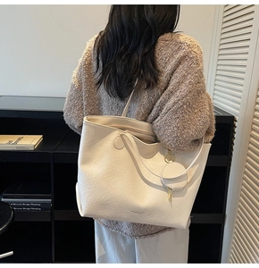 Detail of cream tote bag with wrinkled faux leather texture and round coin purse charm