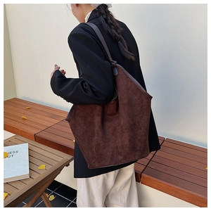 Detail of a large vintage dark brown suede tote bag carried by a model in autumn