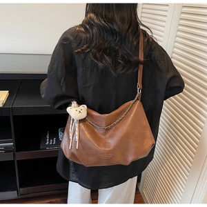 Detailansicht der braunen Leder-Hobo-Tasche mit Goldkette und süßem Bären-Plüschanhänger