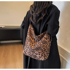 Gros plan d'un sac à bandoulière léopard en tissu doux porté sur un manteau noir
