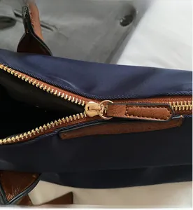 Nahaufnahme des goldenen Reißverschlusses mit braunem Lederzug an blauer Nylontasche