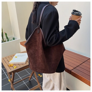 Deep brown suede tote bag styled on model with durable leather shoulder straps