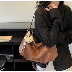 Detail der braunen Hobo-Tasche aus Leder mit goldener Kette und Bären-Anhänger