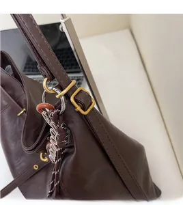 Detail of dark brown leather tote bag with gold hardware and braided strap knots