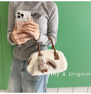 Detail of white fluffy faux fur handbag with a plush rabbit charm and brown leather handles