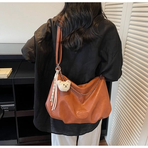 Details der karamellbraunen Falten-Tote-Bag mit Metallkette und süßem Plüschbär-Anhänger
