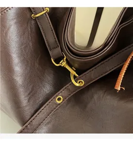 Detail of dark brown lychee grain leather strap with polished gold-tone metal hardware