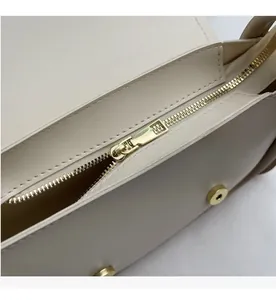 Macro shot of smooth gold zipper and premium stitching on beige leather saddle bag
