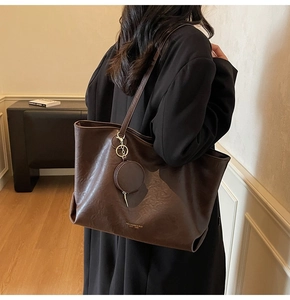 Detail of dark brown leather tote bag with round coin purse and gold logo lettering