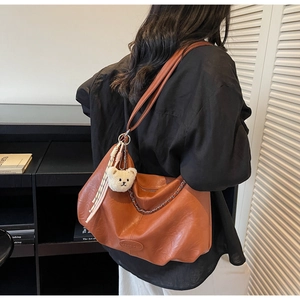 Detailansicht der braunen Hobo-Tasche mit Plüschbären-Anhänger und silberner Kette