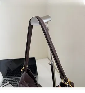 Detail of soft dark brown leather strap with golden metal ring buckle on tote bag