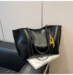 Detail of black faux leather tote bag featuring unique micro-wrinkle texture and colorful beads