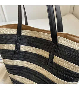 Close-up of durable leather straps with cross-stitch reinforcement on woven tote bag