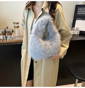 Detail of soft light gray faux fur handbag with elegant curved handle in lifestyle setting