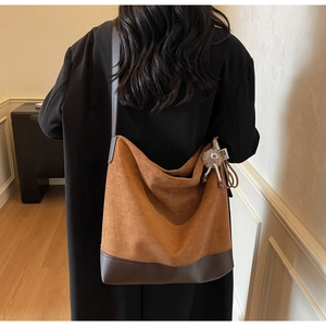 Detailed back view of a caramel suede tote bag featuring brown leather trim and plush charm