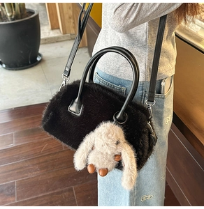 Detail of black faux fur handbag with cute plush bunny pendant and leather strap