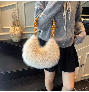 Detalle del bolso medialuna de pelo sintético crema con asa de cuentas de madera naranja