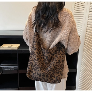 Détail du sac hobo léopard élégant porté avec un pull en maille texturé beige