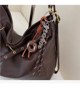 Detail of dark brown leather tote bag with donut charm and vintage metal hardware