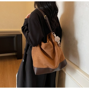 Detailed back view of a large vintage suede tote bag with leather straps and plush charm
