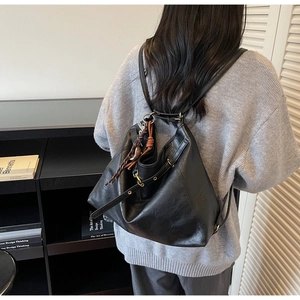 Close-up of black PU leather backpack showing woven rope detail and soft texture