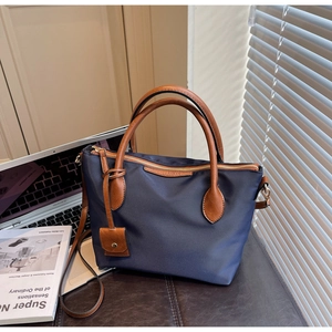 Detail der dunkelblauen Nylon-Beuteltasche mit braunen Ledergriffen am Schreibtisch