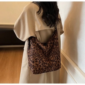 Détail d'un sac seau à imprimé léopard porté avec un trench-coat beige classique pour femme
