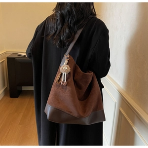 Detailed back view of a large brown hobo tote bag with plush charm and mixed leather textures