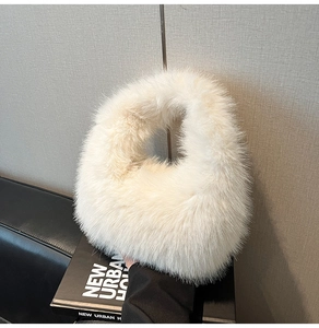 Macro detail of the soft off-white faux fur texture and round handle on the plush handbag