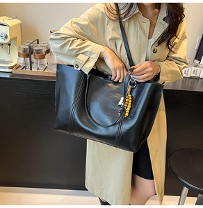 Close-up of black leather tote bag with unique beaded charm and premium textured finish