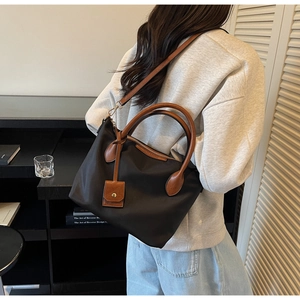 Detailansicht einer schwarzen Nylon-Tasche mit braunen Ledergriffen in modernem Interieur