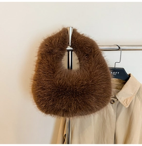 Detail view of a fluffy brown plush handbag displayed on a metallic rack for autumn