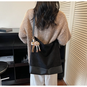 Detail view of black vintage tote bag with plush sheep charm in a lifestyle home setting