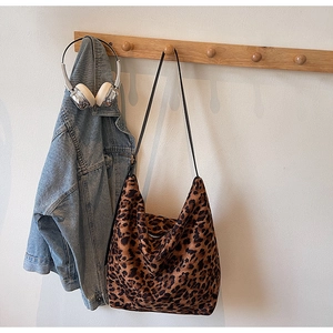 Détail du sac léopard accroché à un crochet en bois avec veste en jean et écouteurs
