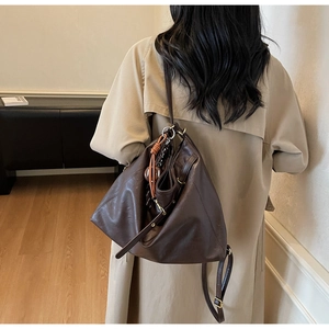 Detail of adjustable strap and golden hardware on chocolate brown leather tote bag