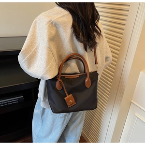 Detail der schwarzen Nylon-Tasche mit braunen Ledergriffen, lässig von einem Model getragen
