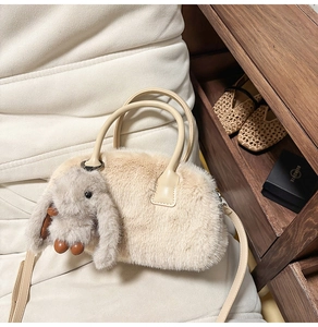 Close-up of beige fuzzy plush handbag with cute bunny charm and leather handles