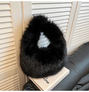 Detail of a fuzzy black faux fur handbag resting on a leather sofa next to a book