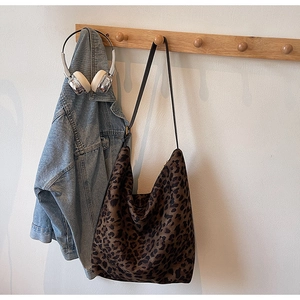 Détail du sac hobo à imprimé léopard suspendu à un crochet en bois dans un décor lifestyle