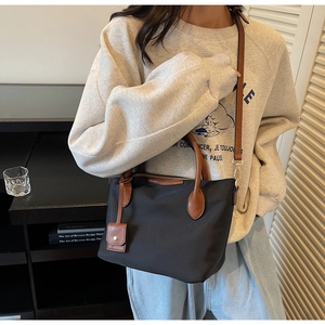 Modell mit schwarzer Nylon-Beuteltasche mit braunen Ledergriffen und Schultergurt