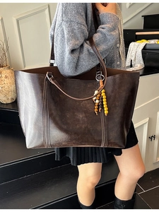 Classic dark brown tote bag in oil wax leather texture with beaded charm pendant