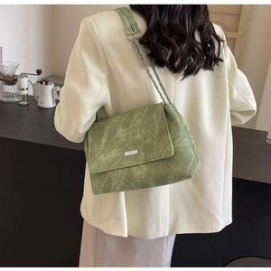 Detail der avocado-grünen Cord-Umhängetasche mit silberner Kette am Model getragen