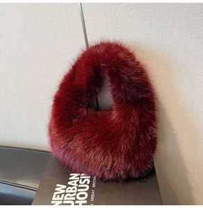 Close-up of fluffy burgundy faux fur handbag on black podium showing soft plush texture
