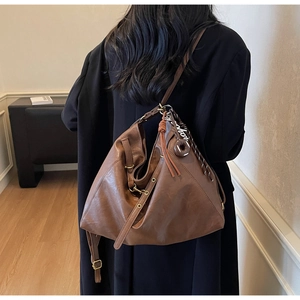 Detail of soft brown leather hobo bag with vintage texture and fashion charm strap
