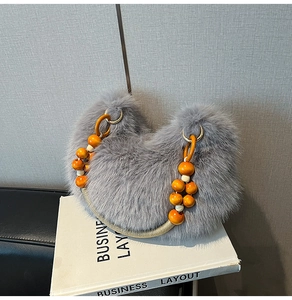 Detalle de bolso de piel sintética gris con asa de cuentas naranjas sobre libros decor