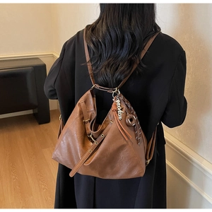 Detail of dark brown leather backpack with golden metal ring and stylish tassel accents