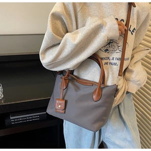 Detail der dunkelgrauen Nylon-Beuteltasche mit braunen Ledergriffen und Schultergurt