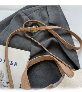 Detail of adjustable brown litchi grain leather strap with gold buckle on bucket bag