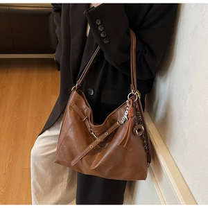 Detail of caramel brown oil wax leather hobo bag with fringe and metal accents
