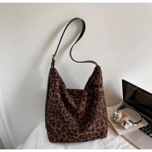 Détail du sac léopard avec bandoulière noire et fermeture éclair sur bureau chic